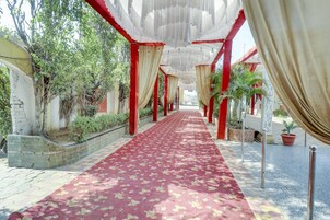 A corridor with a red carpet, red pillars, and white drapes.