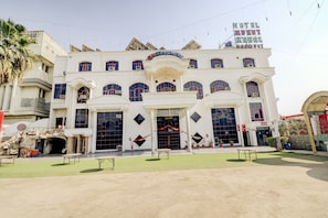 A hotel with a central entrance, multiple windows, and a sign for the reception. - Hotel O by OYO Mukut Mahal (Meerut)