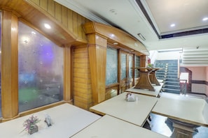 A restaurant interior with wooden paneling, frosted glass windows, and a staircase leading to an upper level. - Hotel O by OYO Mukut Mahal (Meerut)