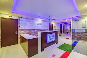A hotel reception area with a reception desk, a 'Welcome Hotel' sign, a 'No Smoking' sign, and a fire extinguisher. - Hotel O by OYO Island (Meerut)