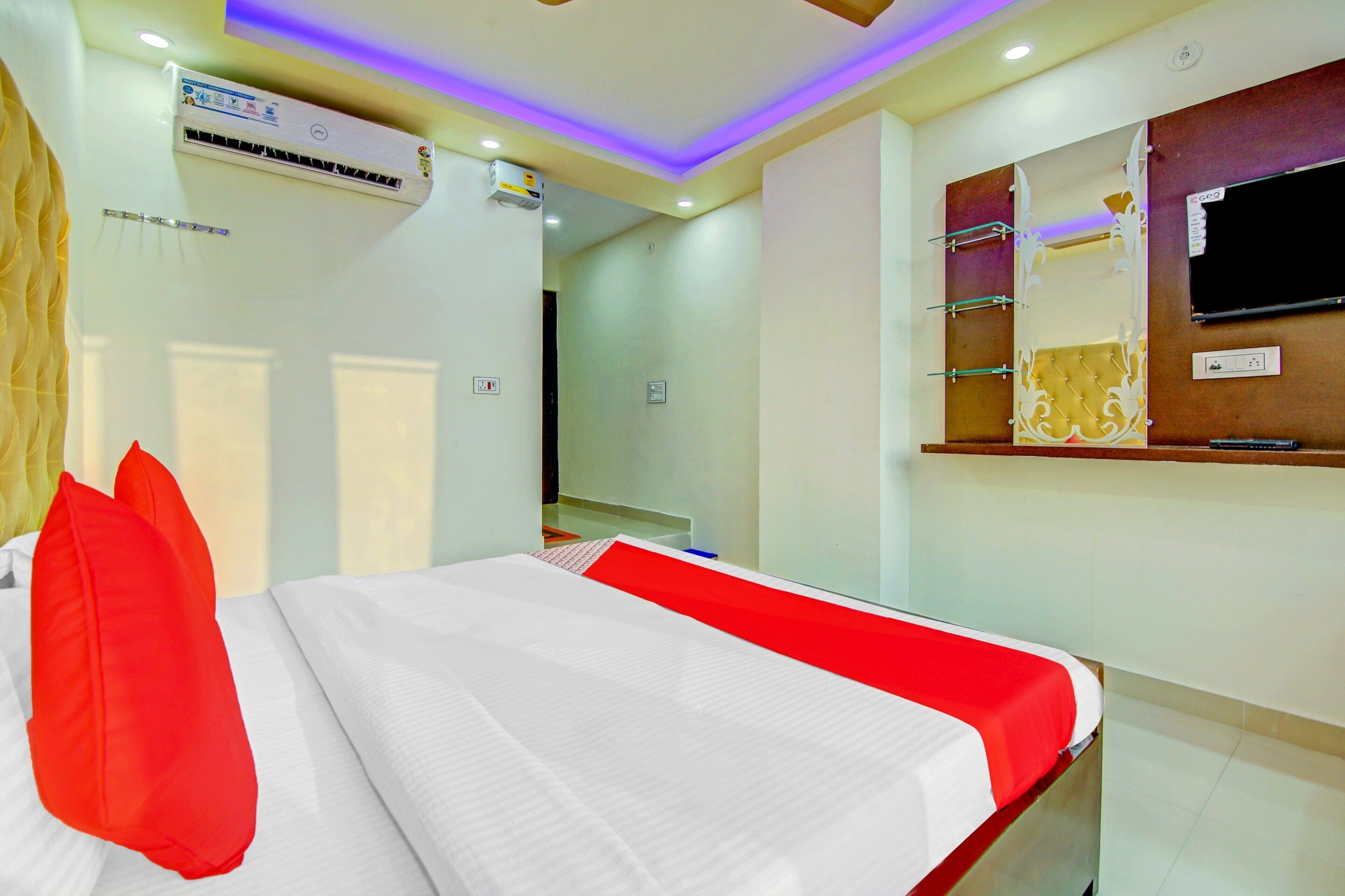 Una habitación de hotel con una cama, un televisor y un estante en la pared.