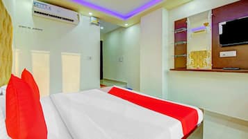 Una habitación de hotel con una cama, un televisor y un estante en la pared.