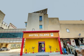 A hotel named 'HOTEL ISLAND' with a bright yellow facade and red accents.