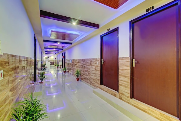 A hotel corridor with a marble floor, wooden doors, and ceiling lights.