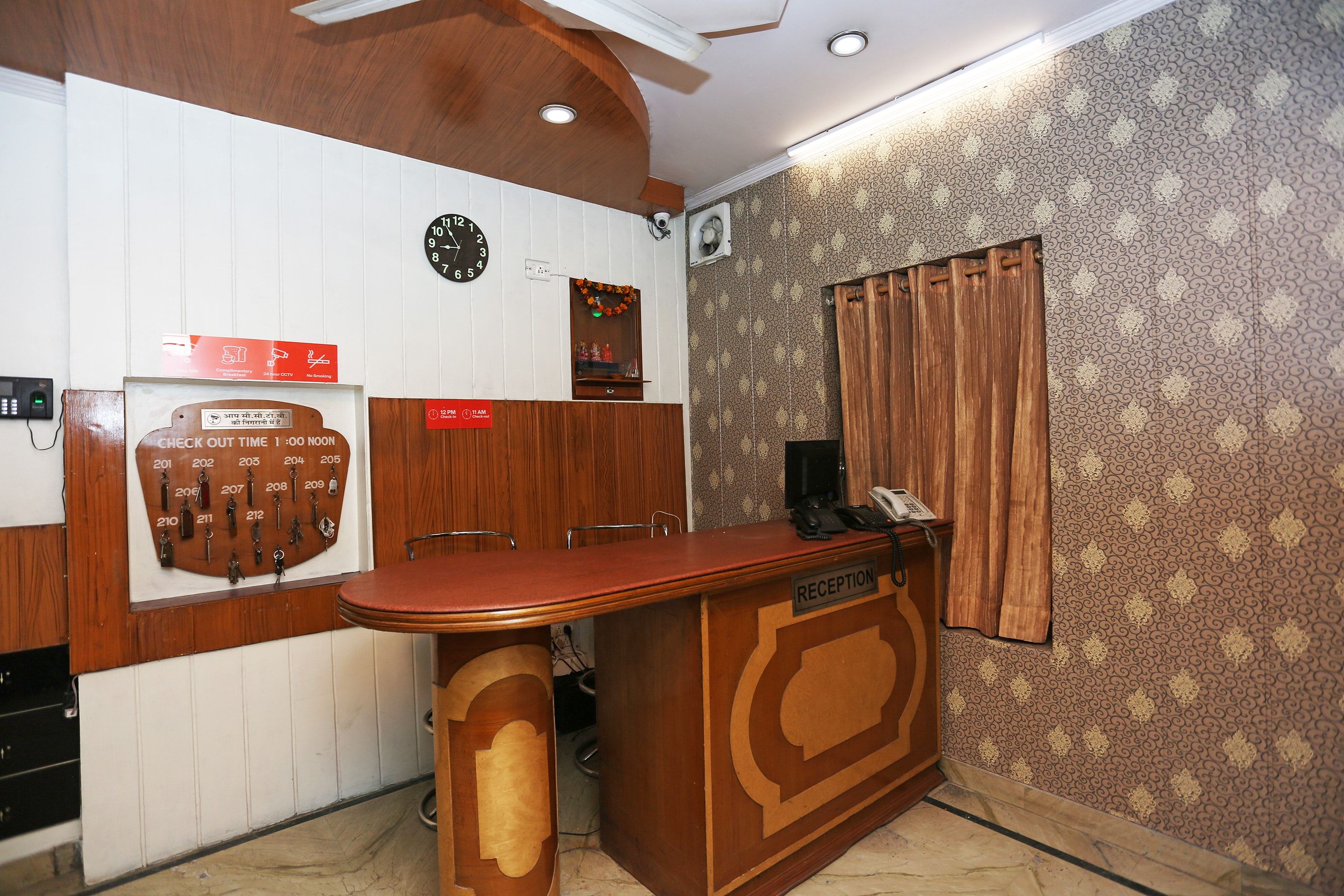 A reception desk with a clock, a key display, and a CCTV sign.