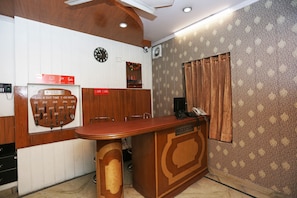 A reception desk with a clock, a key display, and a CCTV sign. - Hotel O Madhur Regency (Meerut)