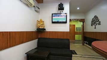 Una sala de estar con un sofá, una mesita, un televisor montado en la pared y una estatua dorada decorativa.