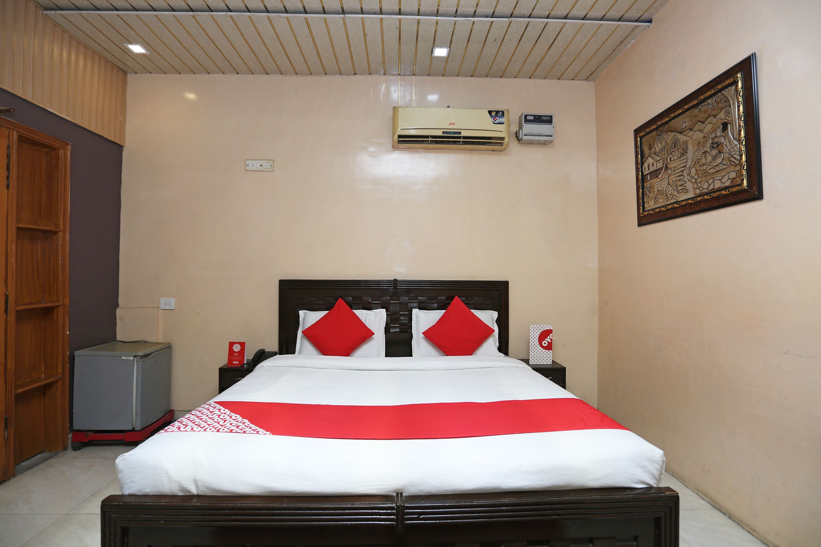 A hotel room with a bed, a nightstand, a wardrobe, and an air conditioning unit.
