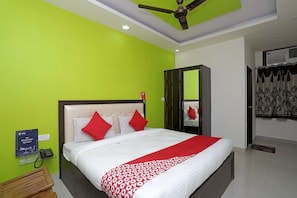A hotel room with a bed, a wardrobe, a mirror, and a ceiling fan. - Super Hotel O by OYO Raj Palace (Meerut)