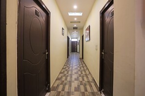 Un pasillo de hotel con piso a cuadros, puertas a ambos lados e iluminación en el techo.