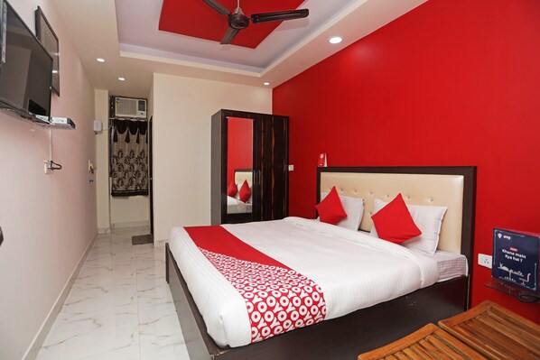 A hotel room with a bed, a ceiling fan, a TV, and a red wall. - Super Hotel O by OYO Raj Palace (Meerut)