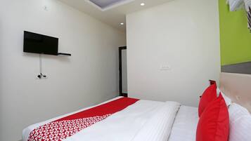 Une chambre d’hôtel avec un lit, un téléviseur fixé au mur et un mur d’accent de couleur verte.