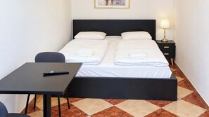 A hotel room with a bed, a desk, a chair, a nightstand with a lamp, and a painting on the wall. - Just the Two of Us Vienna near Westbahnhof (Vienna)
