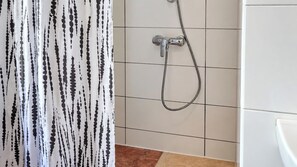 A bathroom with a shower, a tiled wall, and a curtain with a black and white pattern. - Just the Two of Us Vienna near Westbahnhof (Vienna)