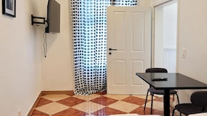 A room with a tiled floor, a white door, a black table, and a black chair. - Just the Two of Us Vienna near Westbahnhof (Vienna)