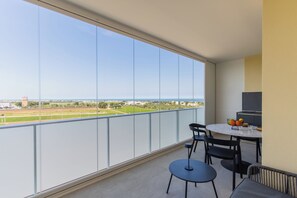 A balcony with a table and chairs, a bowl of fruit, and a view of a green landscape and buildings. - Campo s Guest House Airport (BARI)