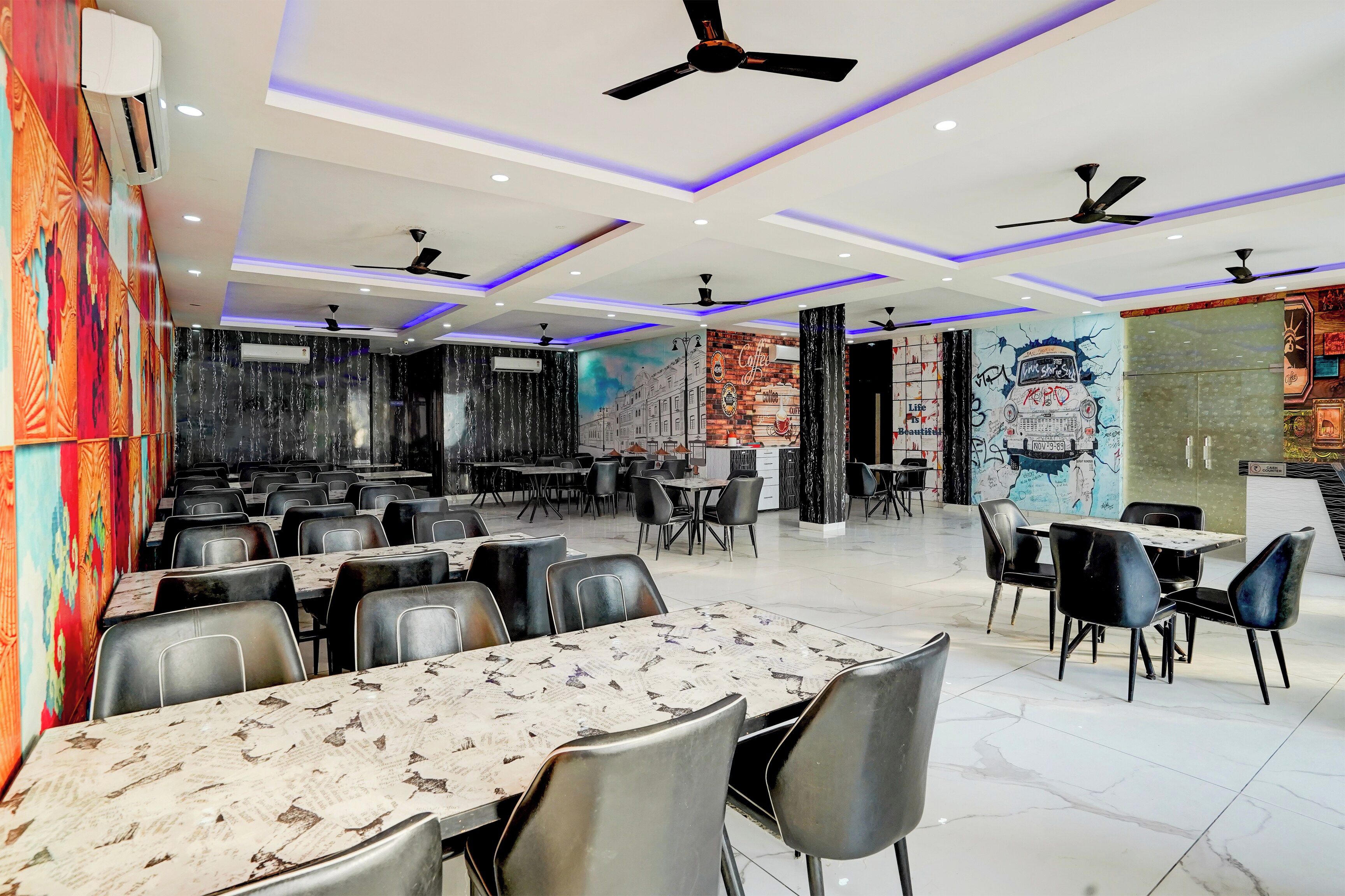 A restaurant with multiple tables and chairs, ceiling fans, and decorative wall murals.