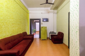 A hallway with two sofas, a television, and a refrigerator. - Hotel O Golden Orchid (Jorhat)