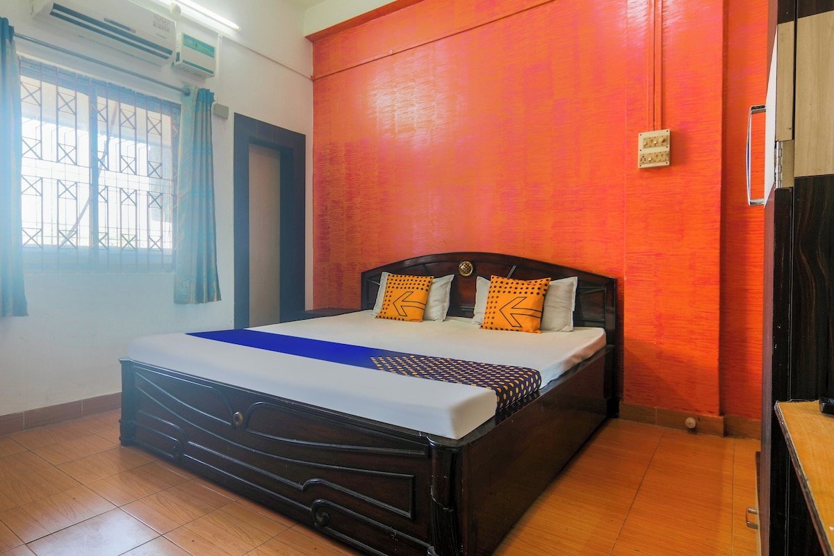 Una habitación de hotel con una cama, un ventanal con cortinas y una pared roja.