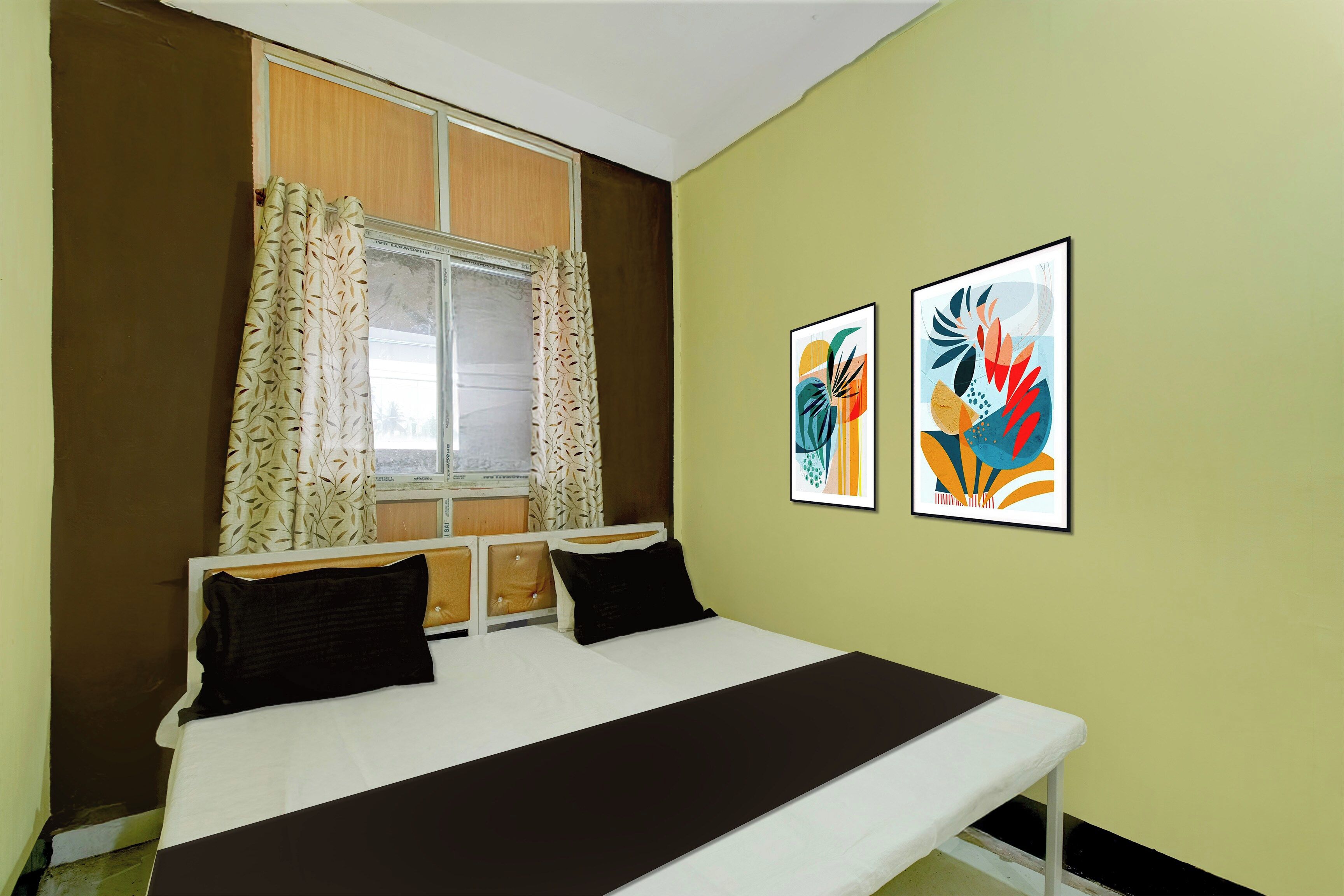 Un dormitorio con cama, dos almohadas, una ventana con cortinas y dos cuadros en la pared.