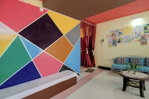 A living room with a colorful geometric wall design, a blue sofa, and a small table with a plant.