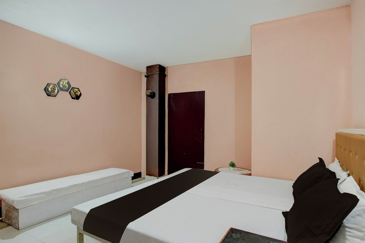 A bedroom with a bed, a bench, a door, and wall decorations.