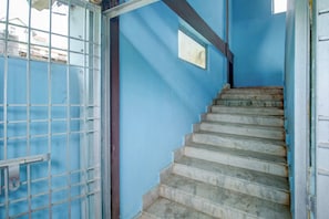 A staircase with a metal railing, leading to a door with a window. - Hotel O RB Atithisala (Jorhat)