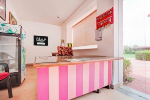 A reception desk with a pink and white striped design, a glass top, and a calendar on the wall.