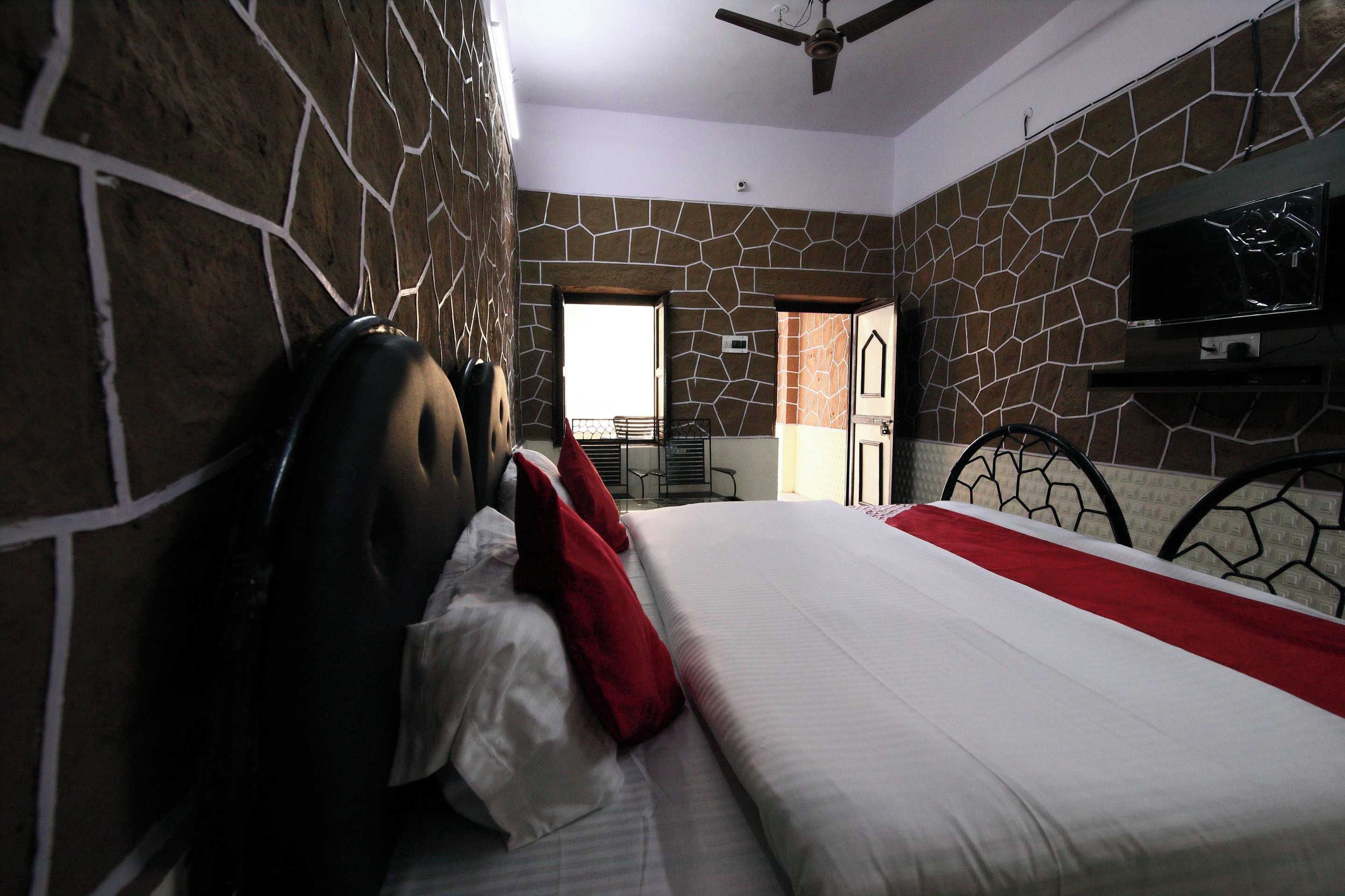 A bedroom with a bed, a TV, and a view of the outside.