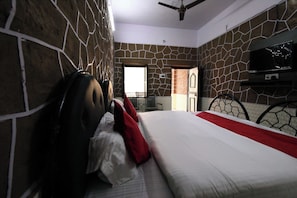 A bedroom with a bed, a TV, and a view of the outside.