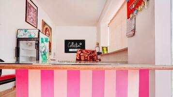 A reception area with a counter, a refrigerator, a wall-mounted calendar, and a sign that reads 'Collection'.