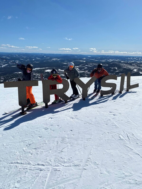 A group of people standing on a snowy mountain with a large 'TRYSIL' sign in the foreground.