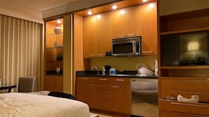 Ein Hotelzimmer mit Bett, Schreibtisch, Mikrowelle, Kühlschrank und Fernseher.
