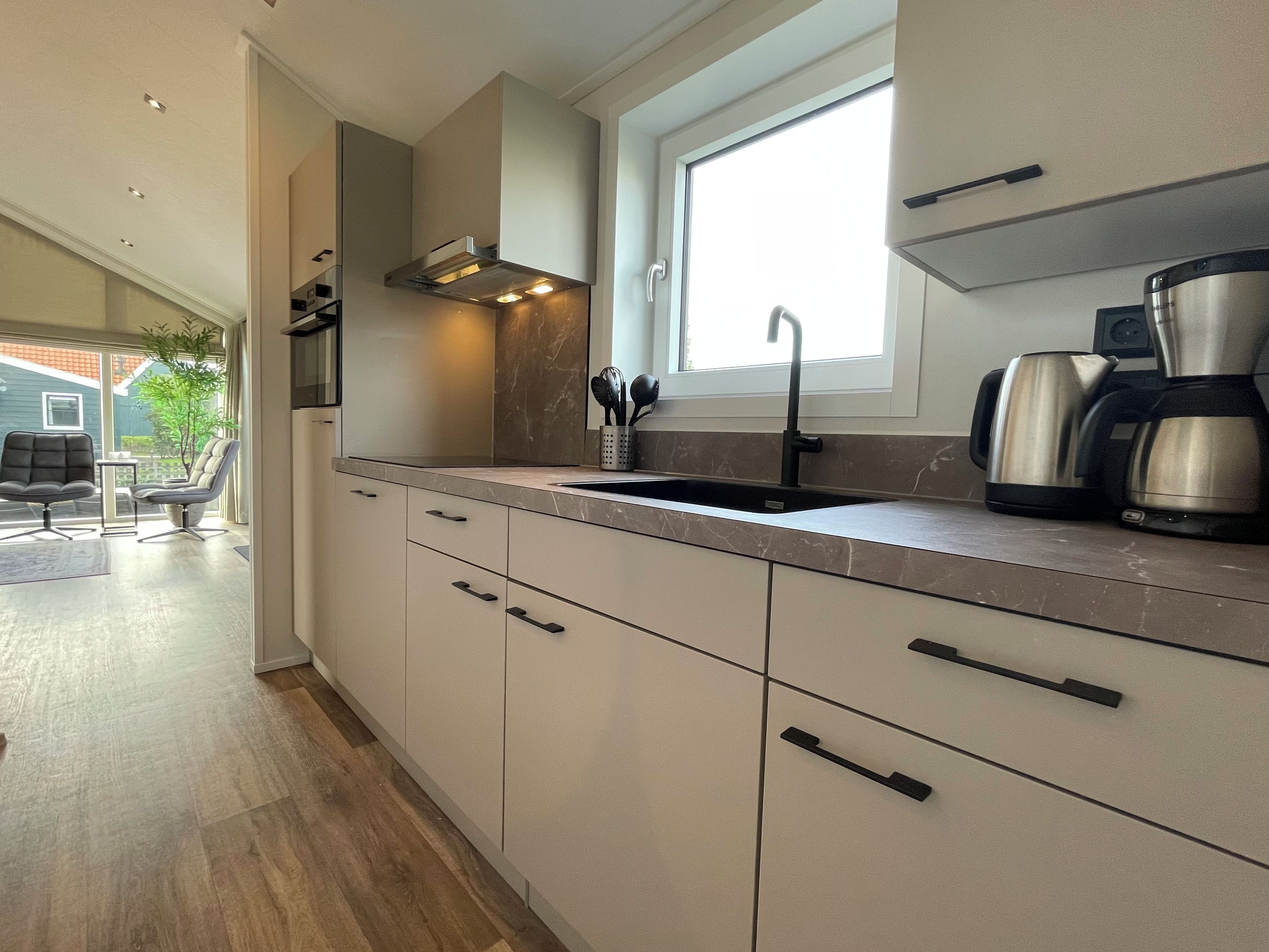 A modern kitchen with a window, stainless steel appliances, and a built-in oven.