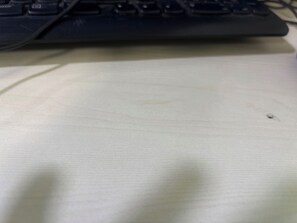 Un teclado sobre una superficie plana, con una tecla visible y un objeto pequeño encima.