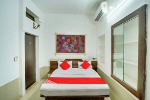 Quarto de hotel com cama, janela, colcha fixada na parede e porta.