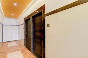 Un pasillo con piso de madera, dos puertas de madera oscura y una pared de color claro.
