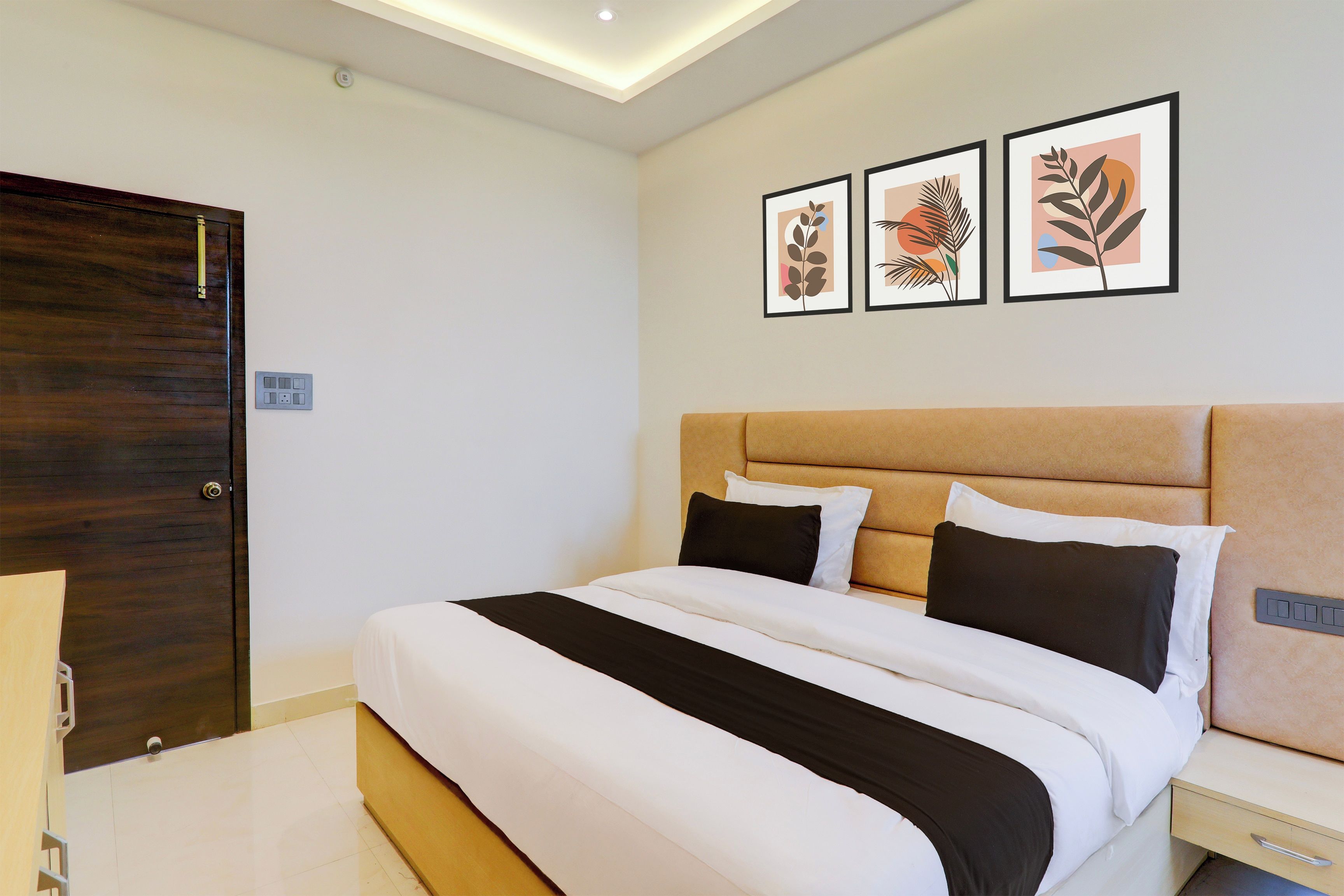 A neatly made bed with a headboard, a bedside table, and a wall-mounted power outlet.