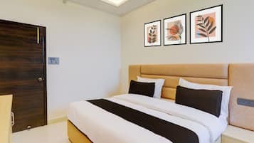 A neatly made bed with a headboard, a bedside table, and a wall-mounted power outlet.