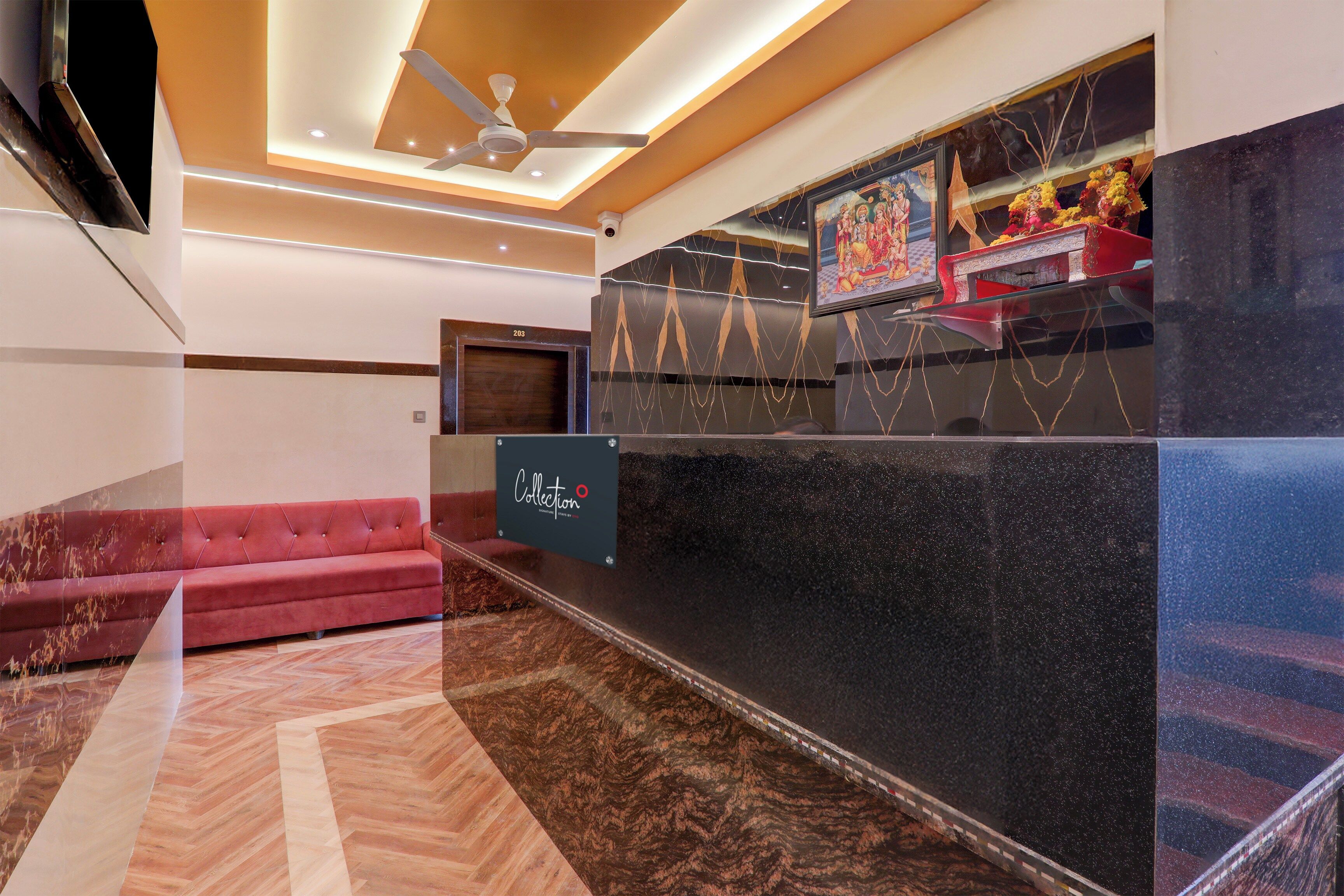 A hotel lobby with a red sofa, a reception desk, and a ceiling fan.