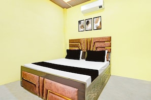 Ein Bett mit Holz Kopfteil, einer weißen Matratze und schwarzen und weißen Kissen.