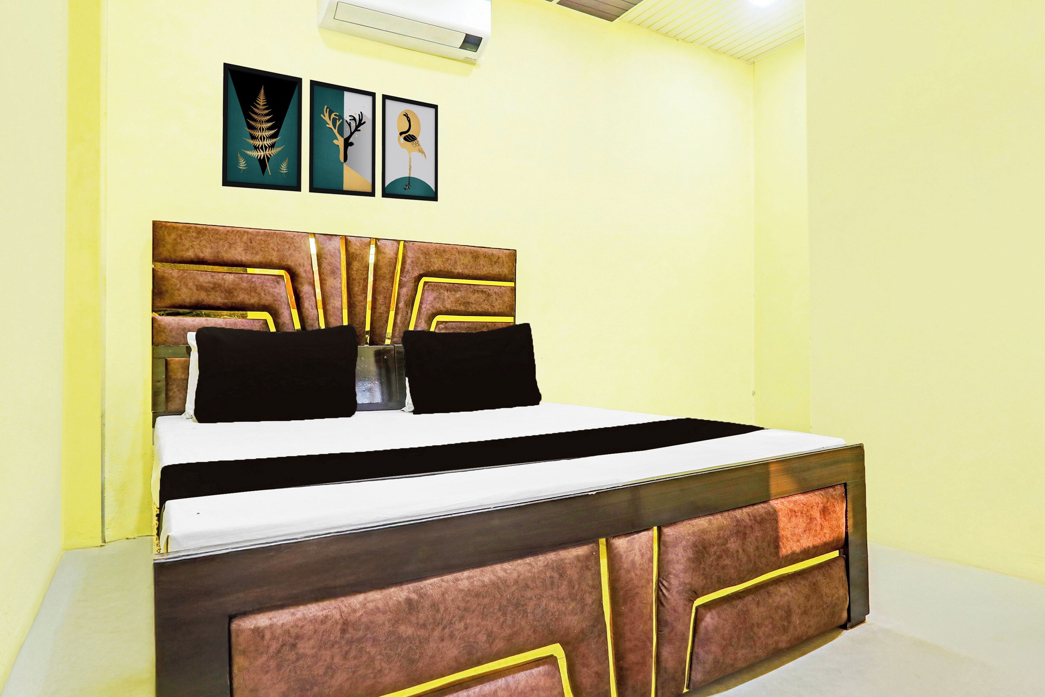 A bed with a headboard, a bedside table, and two wall-mounted pictures.