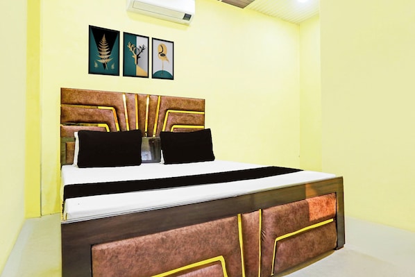 A bed with a headboard, a bedside table, and two wall-mounted pictures.