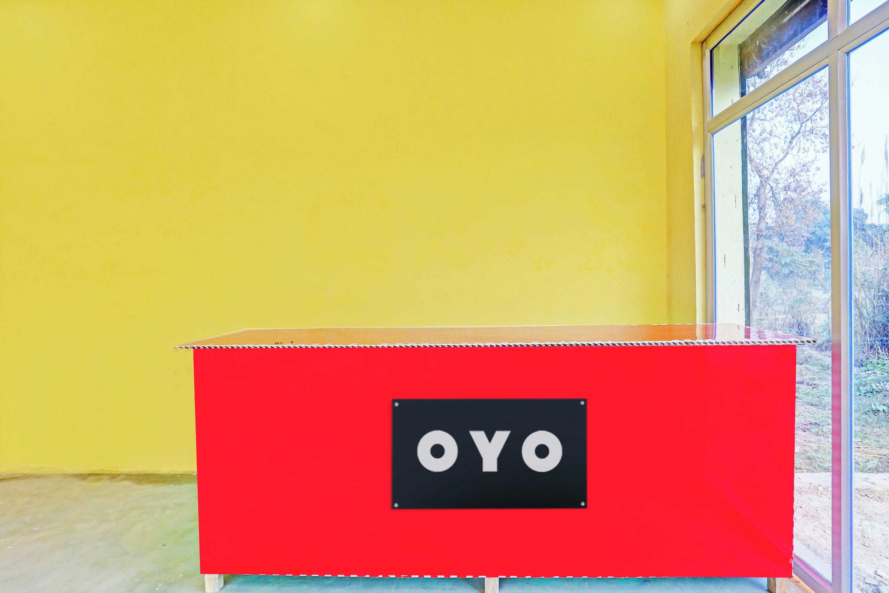 A red storage box with the label 'OYO' on a yellow wall next to a window.
