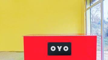 A red storage box with the label 'OYO' on a yellow wall next to a window.