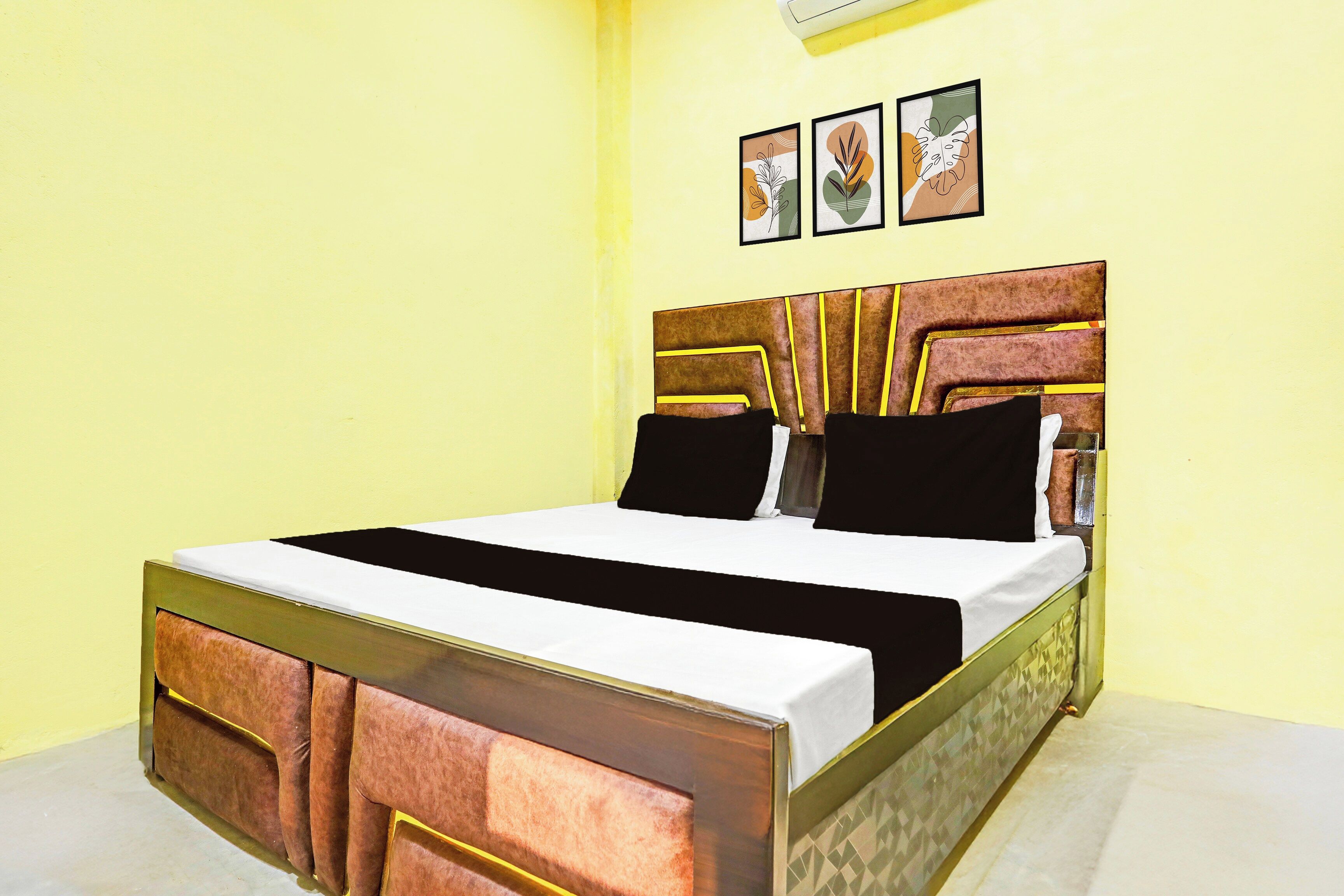 A bed with a headboard, a bedside table, and two framed pictures on the wall.