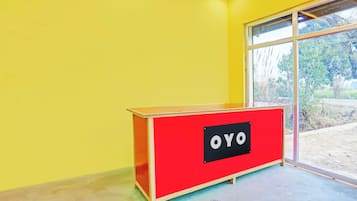 A red OYO branded desk in a room with yellow walls and a large window.