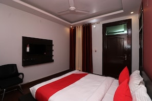 Een hotelkamer met een bed, een aan de muur bevestigde televisie, een deur en een stoel.