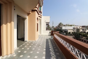 A building with a balcony, a tiled floor, and a view of other buildings in the distance. - Hotel O Krishna Inn (Lucknow)