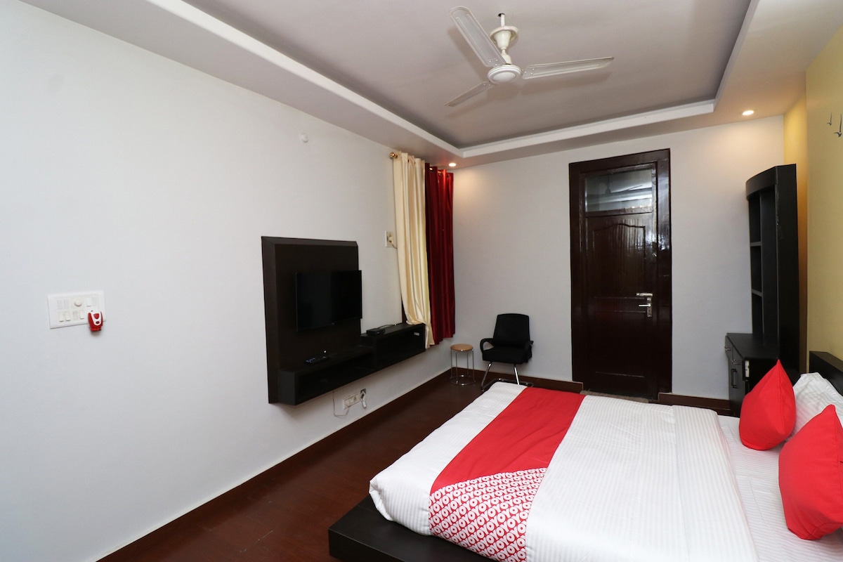 Una habitación de hotel con cama, televisor, escritorio, silla, armario y puerta.